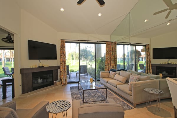 Settle into this spacious living room where vaulted ceilings and large glass doors invite natural light to flood the space. Your private patio awaits just beyond, framed by lush greenery and open sky.