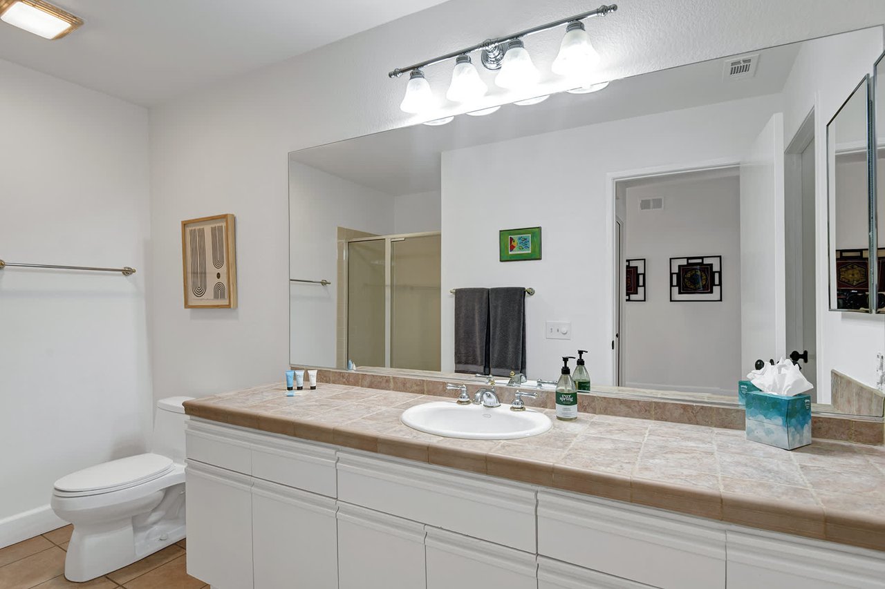 Step into your bright, spotless bathroom with its long vanity counter and generous mirror—perfect for getting ready each morning.