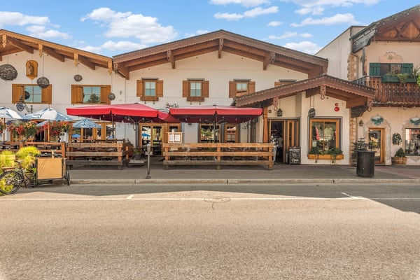 Charming Alpine-style building with traditional wood accents and inviting outdoor seating, located in a picturesque mountain village setting.