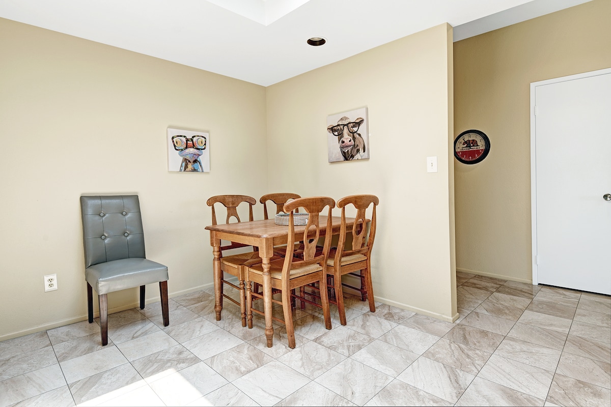 Gather around the warm wooden dining table where meals become memories. The bright skylight above floods your dining space with natural light, creating the perfect setting for morning coffee or evening conversations.
