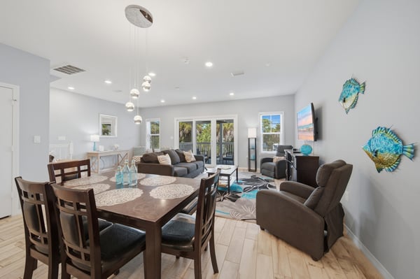 Gather around the inviting dining table or sink into plush seating as natural light spills through glass doors. Coastal-inspired decor and modern touches create a bright, welcoming space perfect for your getaway.