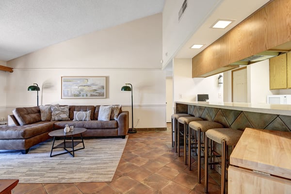 Gather in your stylish open living space where a plush leather sectional invites you to unwind. Bar seating creates the perfect spot for morning coffee or evening conversations while vaulted ceilings add an airy, spacious feel.