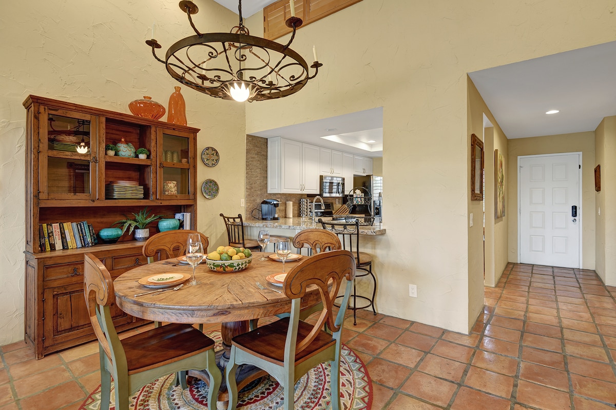 Step into your welcoming dining space, where a rustic table awaits your family meals under charming wrought-iron lighting. The open layout flows into a bright, fully equipped kitchen—perfect for preparing your favorite dishes together.
