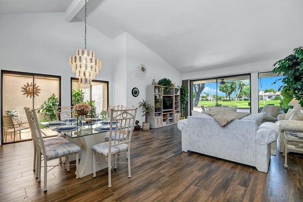 Soaring ceilings and rich wood floors create an open, airy ambiance where your family can gather for meals and relaxation. Through the glass doors, green lawns and palm trees invite you to step outside and soak in the sunshine.