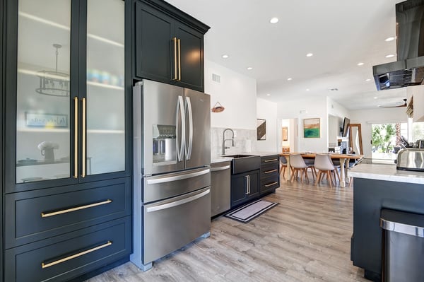 You'll love cooking in this modern kitchen, where sleek navy cabinetry and stainless appliances meet a bright, open-concept layout perfect for gathering around the breakfast table.