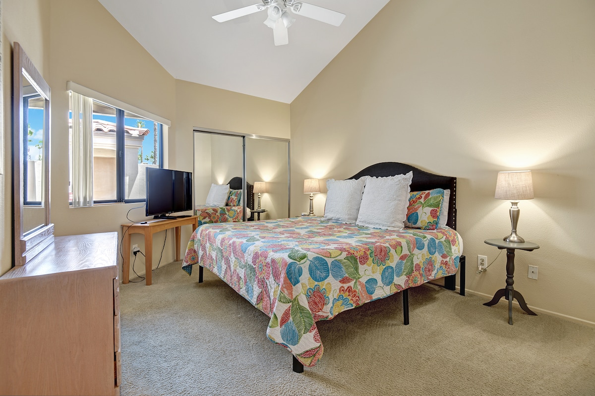 Unwind in your cozy bedroom with vaulted ceilings and natural light streaming through large windows. The cheerful floral bedding and thoughtful touches create a welcoming retreat after a day of exploring.
