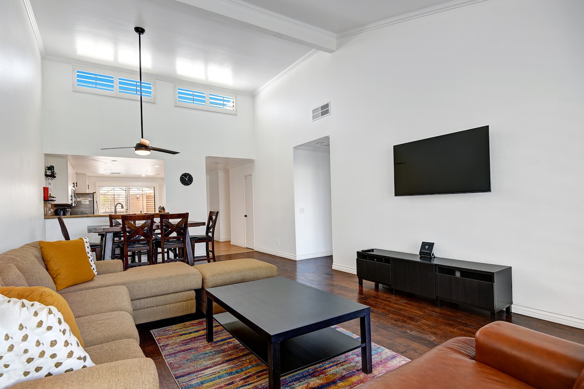 Unwind in your spacious living room with vaulted ceilings, hardwood floors, and plenty of natural light streaming through high windows—perfect for relaxing after a day of exploring.