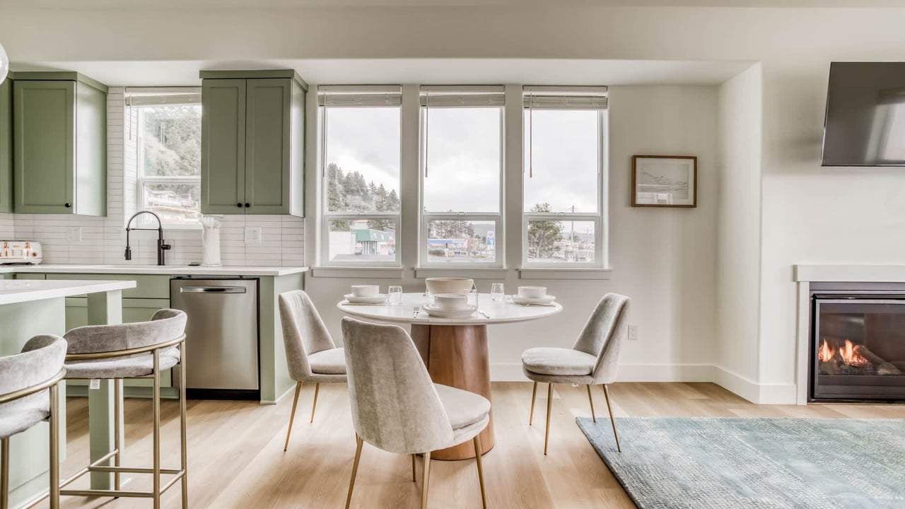 Start your morning at this charming dining table with coffee and sunlight streaming through large windows. The sleek kitchen and cozy fireplace create the perfect space for dining and relaxing.