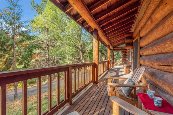 Step out onto your private wrap-around deck and unwind among the pines—rustic wooden seating under soaring timber beams invites quiet moments and mountain air.