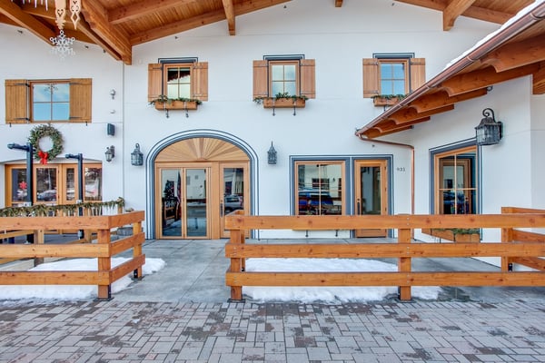 A charming property entrance features Alpine-style architecture with warm wood accents, shuttered windows adorned with flower boxes, and festive seasonal touches that greet you upon arrival.