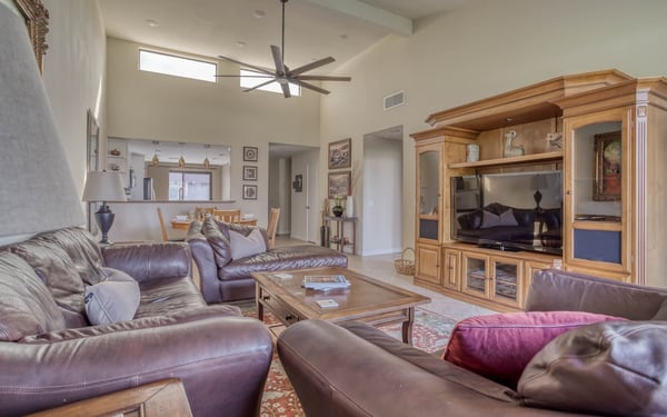 Settle into your spacious living room with plush leather seating and an entertainment center ready for movie nights. Natural light flows through the high windows, while ceiling fans keep you comfortable year-round.