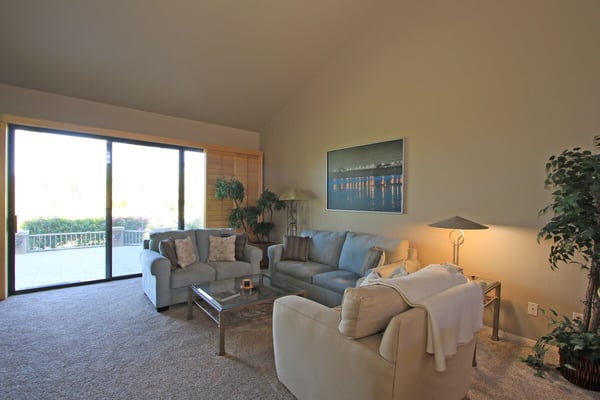 Relax in your spacious living room with plush seating and expansive sliding doors opening to your private balcony, where treetops and open skies create a serene retreat.
