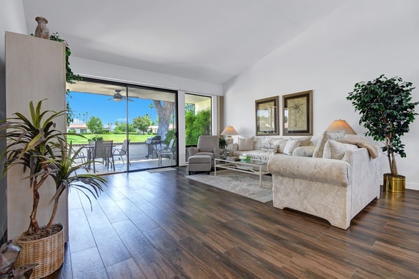 Bright, open living space where you can unwind on plush seating, enjoy natural light pouring through expansive glass doors, and step outside to your private patio overlooking lush green lawns.