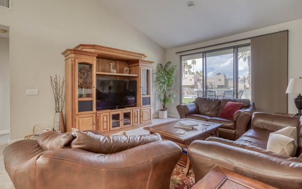 Sink into plush leather sofas in your bright, airy living room, where sunlight streams through sliding glass doors and palm trees sway in the distance. Perfect for unwinding after a day of desert adventures.