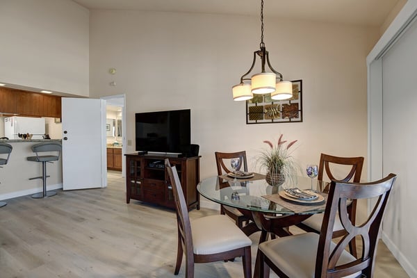 Gather around the glass-topped dining table for memorable meals in this light-filled open space, featuring elegant wood furnishings and modern touches throughout.