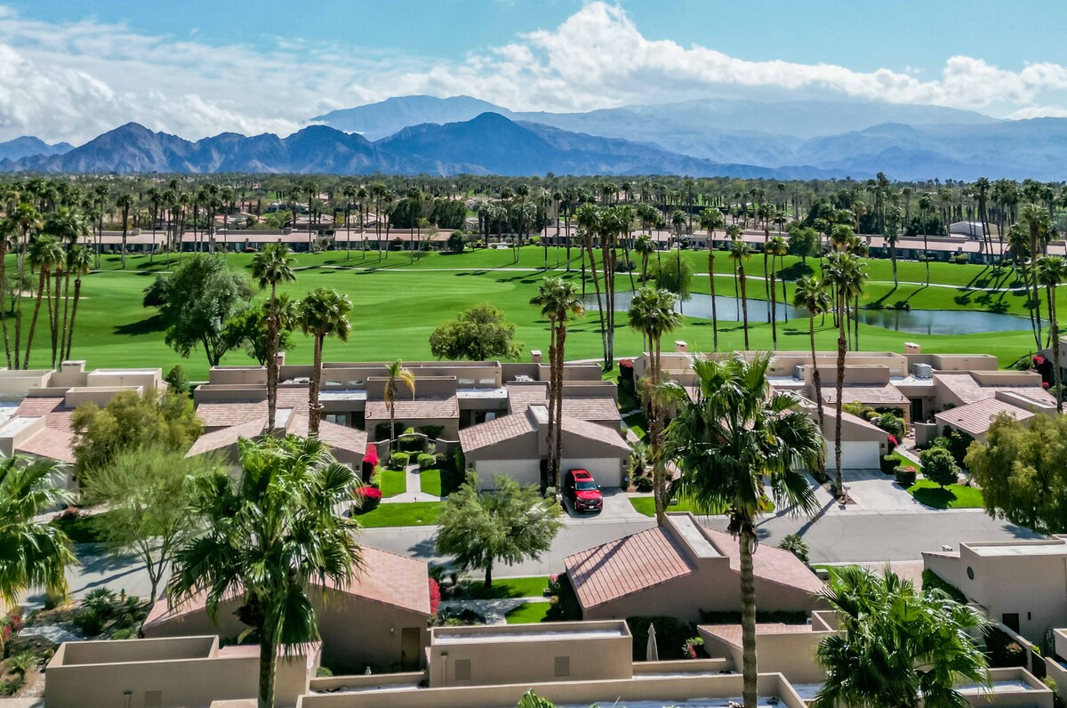 This desert community features palm-lined streets, lush golf course fairways, and dramatic mountain vistas framing the entire neighborhood in every direction.