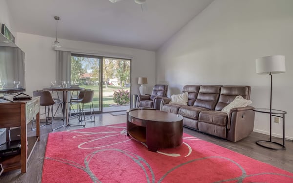 Settle into your spacious living area, where natural light floods through large glass doors and invites you to enjoy the tree-lined view. The open layout connects your dining, living, and kitchen spaces for effortless relaxation.
