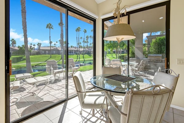 Step into your bright dining space with expansive glass doors framing swaying palms and lush fairway greens—your serene backdrop for every meal.