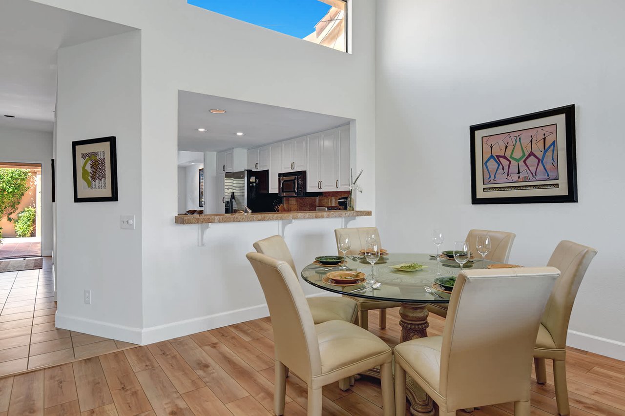 Gather around this elegant glass-top dining table, where natural light pours in through soaring ceilings. The open layout connects you to the kitchen, making meal prep and conversation flow effortlessly together.