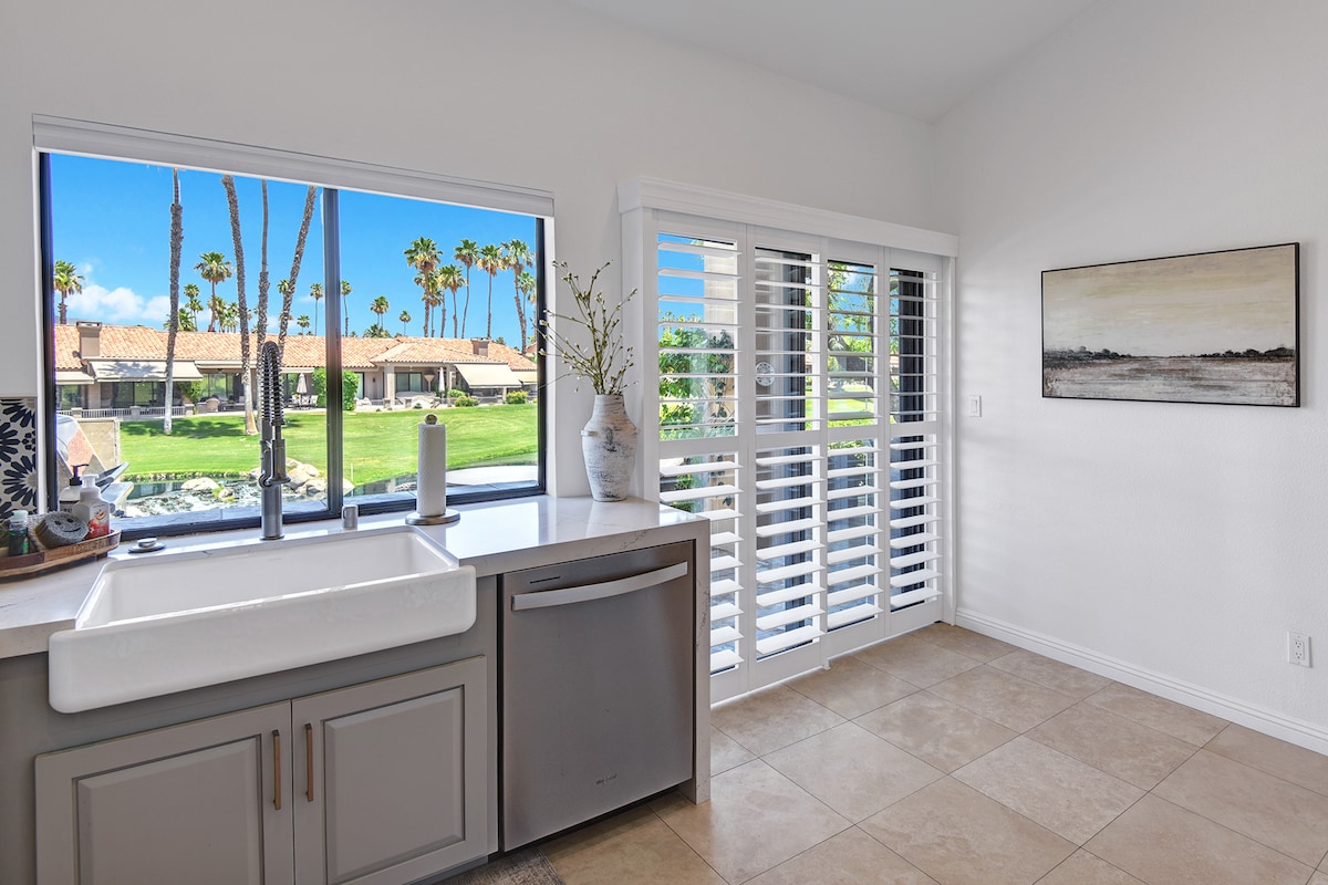 Sunlight fills your kitchen through large windows framing towering palms and lush green lawns—perfect for morning coffee while soaking in those desert oasis views.