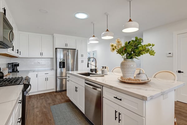 Your bright, welcoming kitchen features a large island with fresh flowers, gleaming marble counters, and top-tier appliances. Gather here for morning coffee or whip up delicious meals in this sunlit space.