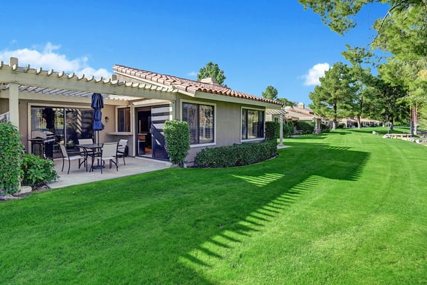 A peaceful residential property with terracotta tile roofing, private patio seating, and pristine landscaped grounds stretching across the neighborhood.