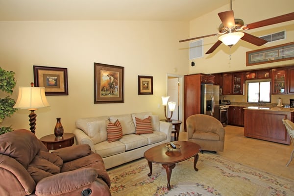 Settle into plush sofas in this spacious living room with high ceilings and rich wood finishes. The open layout flows seamlessly to a well-equipped kitchen, ideal for relaxing or entertaining.