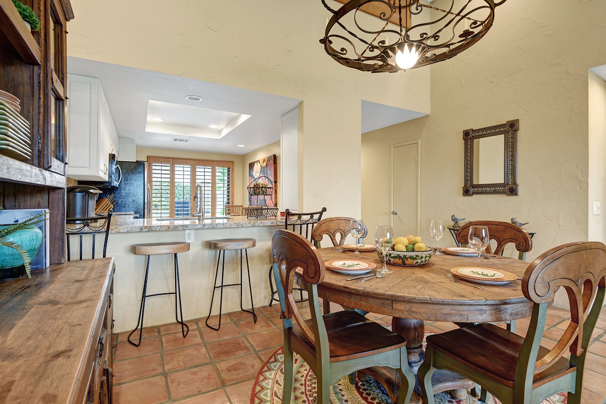Gather around the rustic charm of your private dining space, where a farmhouse table invites memorable meals beneath an ornate chandelier. The adjacent kitchen seamlessly connects for easy entertaining.