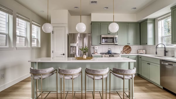 Beautifully appointed chef's kitchen with soft sage cabinetry and gleaming countertops. Natural light floods through plantation shutters, while the island offers the ideal gathering spot.