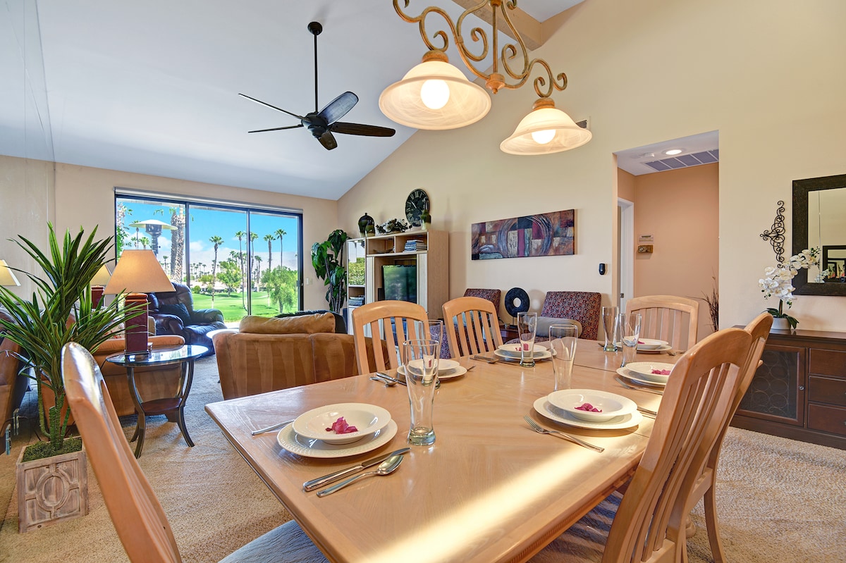 Gather around your beautifully set dining table and enjoy meals together beneath the warm glow of elegant lighting and soaring vaulted ceilings, with sweeping views of palm-lined greens just beyond the glass.
