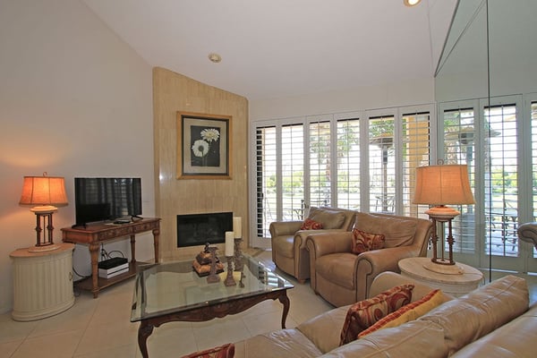 Settle into this inviting living room, where plush seating and warm lighting create your perfect retreat. The cozy fireplace and shuttered doors opening to your private patio make it easy to unwind in comfort.