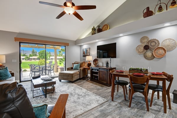 Step into your inviting open-concept living and dining area, where warm tones, comfortable seating, and a peaceful golf course view through sliding glass doors set the scene for your relaxing getaway.