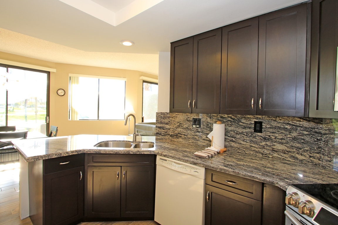 Bright and inviting kitchen with elegant granite counters, dark cabinetry, and modern appliances—everything you need to whip up your favorite meals during your stay.