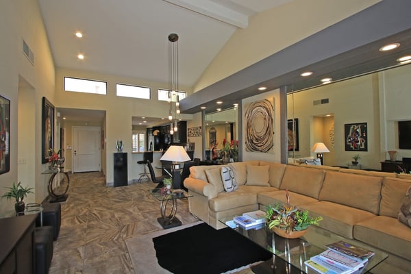 Step into your spacious living room with soaring vaulted ceilings and elegant pendant lighting that creates a warm, inviting atmosphere for relaxation and conversation.