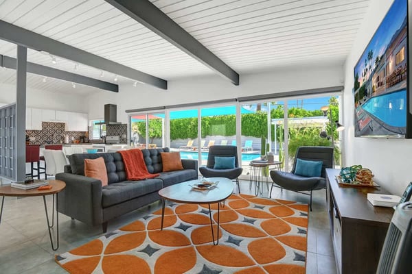 Stretch out in your bright, open living space where floor-to-ceiling windows frame the lush greenery and sparkling pool beyond. Mid-century style meets modern comfort here.