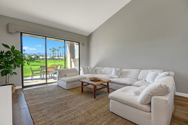 Sink into plush white seating and gaze out at lush green fairways framed by swaying palms—your perfect retreat awaits.