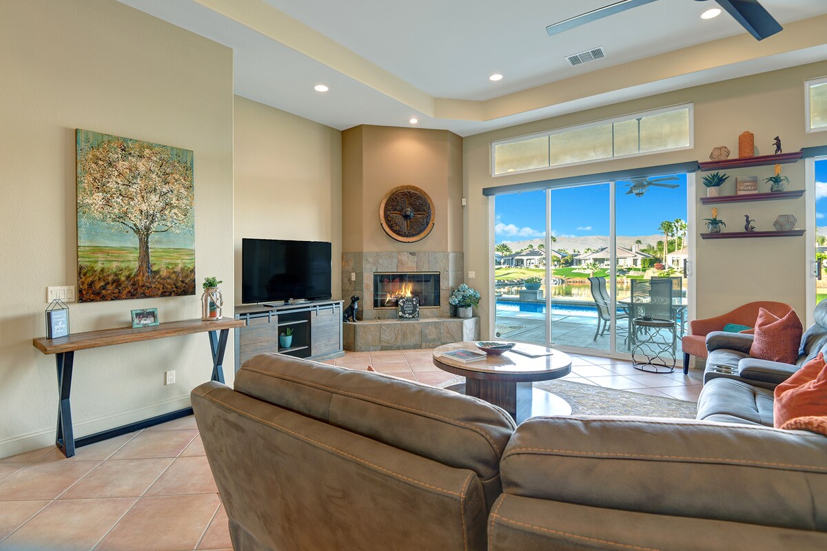 Settle into your inviting living room with cozy seating and a warm fireplace. Beyond the glass doors, your private pool awaits under sunny skies, perfect for relaxing after exploring the area.