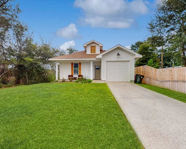 A charming single-family home with a bright, welcoming entrance and spacious lawn, nestled in a peaceful neighborhood surrounded by mature trees.