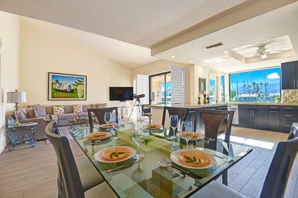 You'll love gathering around this elegant glass dining table, where natural light pours in through expansive windows and palm trees sway just beyond your view. The open layout flows seamlessly into your living space and modern kitchen.