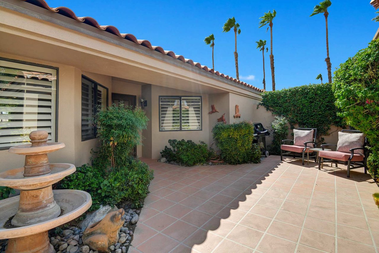 The property's private patio offers a peaceful retreat, framed by lush greenery, towering palms, and southwestern charm—an inviting outdoor space to unwind under the desert sun.