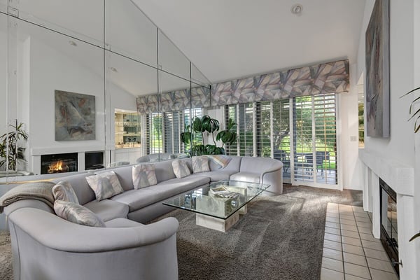 Settle into this elegant living space where natural light streams through plantation shutters and a cozy fireplace creates the perfect retreat for your relaxation.