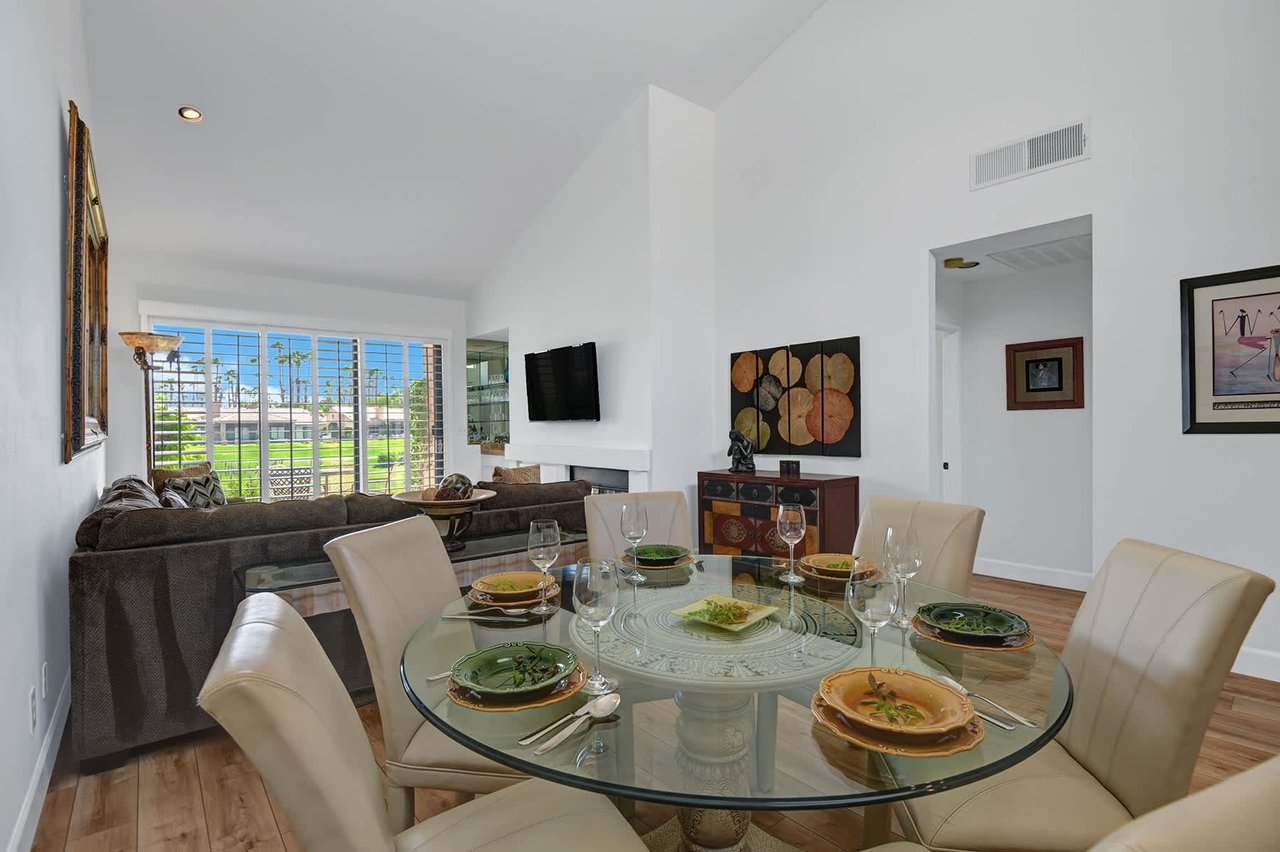 Gather with your group at this spacious glass dining table, perfectly set for shared meals in a bright, open living space with vaulted ceilings and sunny views.