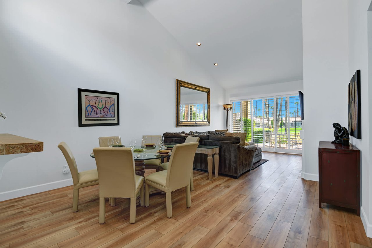 Gather around the dining table with natural light streaming through plantation shutters, then unwind in your open living space with warm hardwood floors and vaulted ceilings overhead.