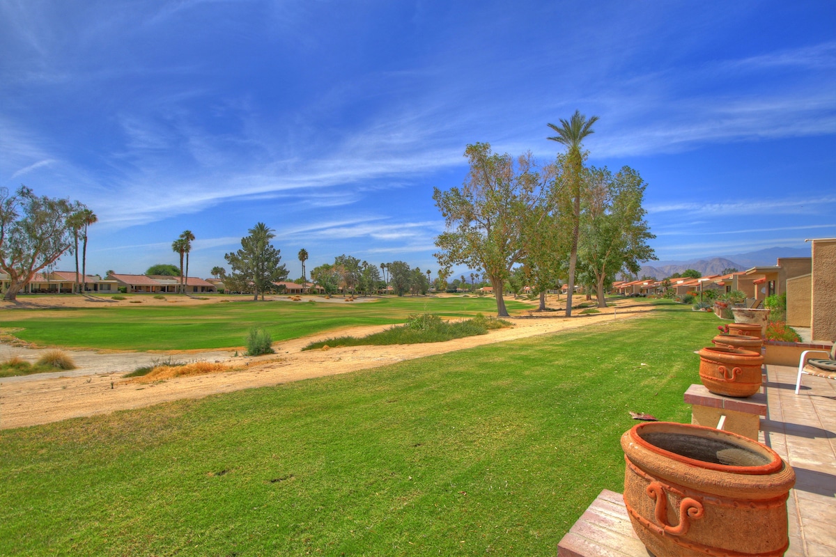 The property sits within a resort community featuring manicured fairways, palm trees, and mountain views on the horizon.