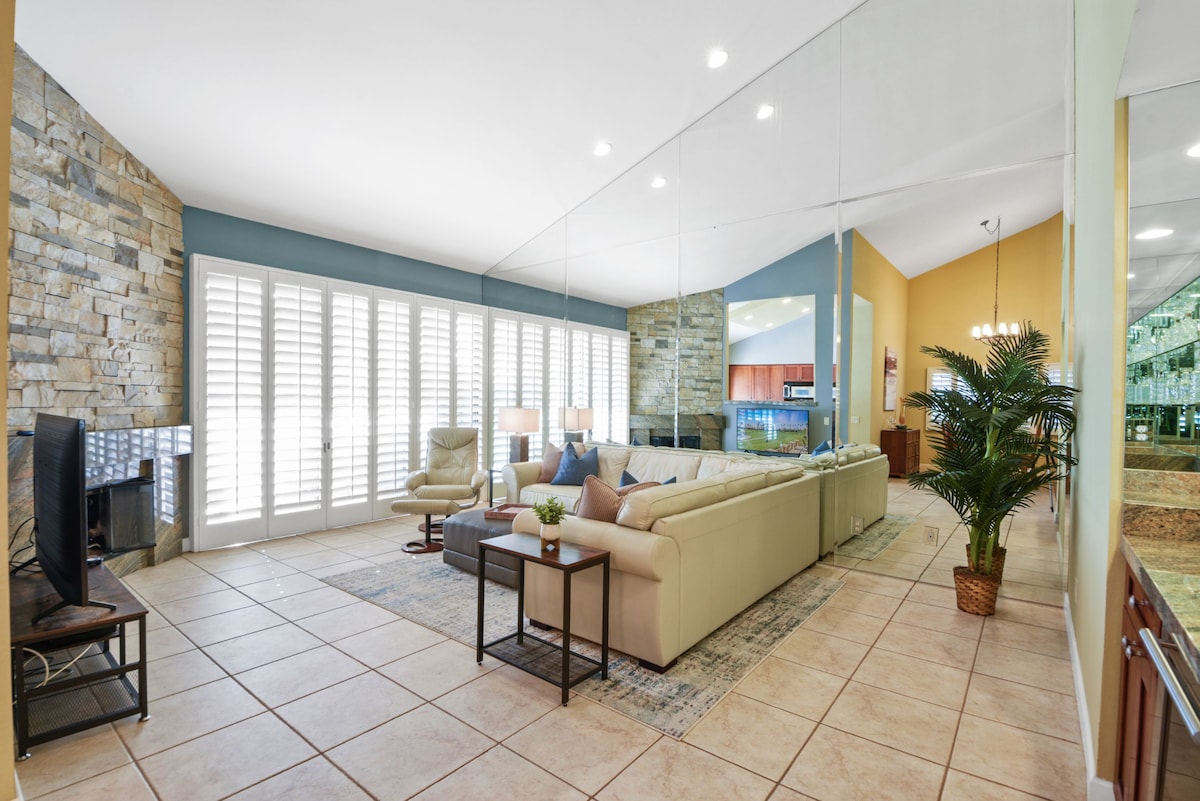 Unwind in your spacious living area with soaring ceilings, natural stone accents, and abundant natural light streaming through plantation shutters—your perfect spot to relax after a day of exploring.