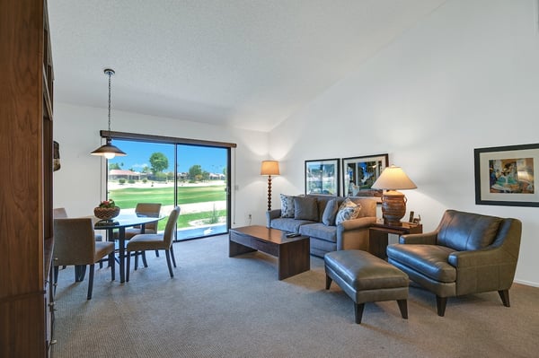 Relax in your bright living space where comfortable seating and a dining area open to beautiful golf course views through expansive glass doors—your peaceful retreat awaits.