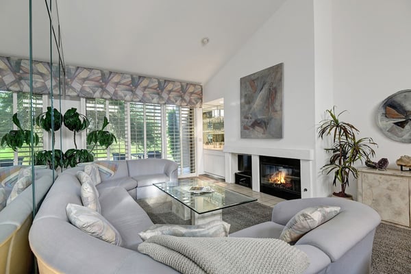 Settle into plush seating by the fireplace's glow, where vaulted ceilings and garden views create your serene retreat. It's the perfect spot to unwind and feel completely at home.