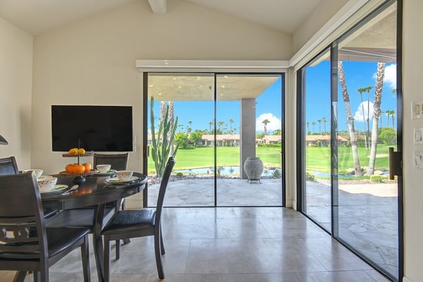 Step from your dining area onto a sun-drenched patio overlooking lush greens framed by swaying palms, where indoor-outdoor living feels effortlessly yours.