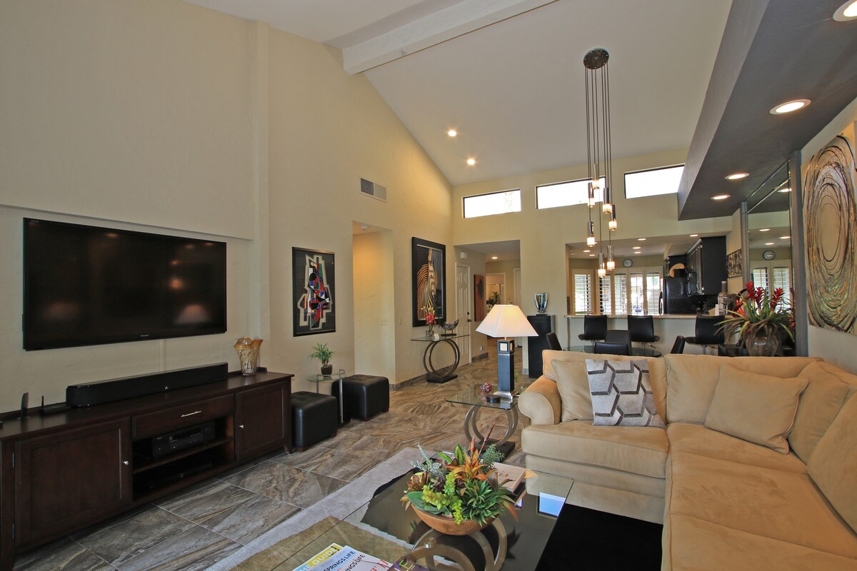 Settle into your stylish living room with vaulted ceilings and modern decor. The open layout flows seamlessly to the kitchen, creating a bright, inviting space where you'll love to unwind after exploring.