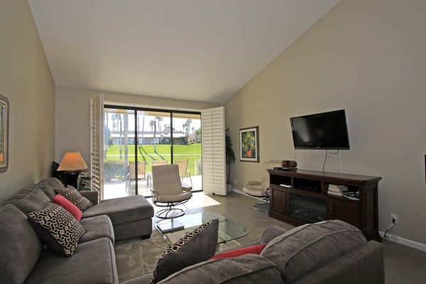 Relax in your bright, open living space where glass doors frame lush green fairways just steps from your patio—perfect for unwinding with natural light and resort views.